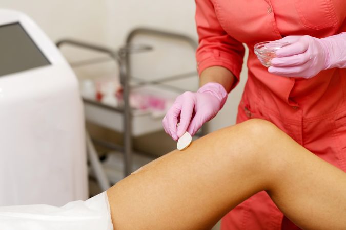 Cold gel applied to client’s thigh before hair removal procedure
