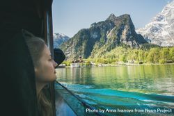 Young woman traveler looking out of window over mountains and water on boat trip 5nQzn0