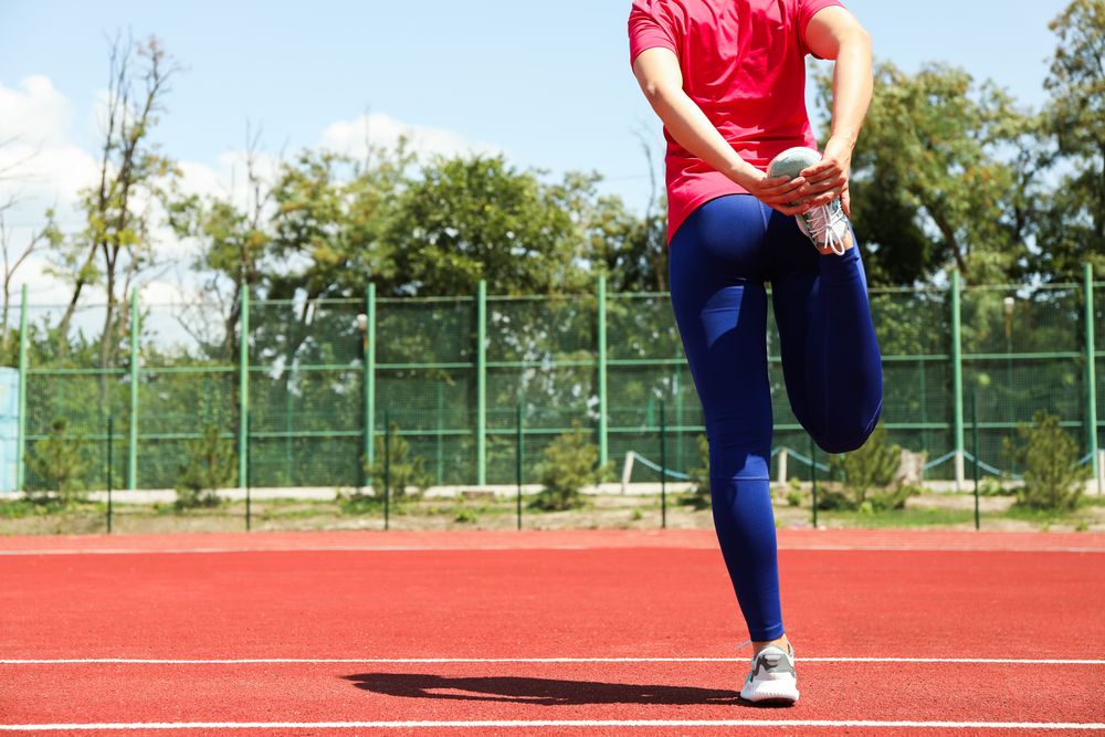 Sporty woman doing stretching leg before jogging, space for text