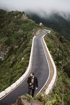 Bearded photographer looking away on mountain road