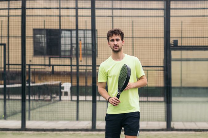 Young man playing paddle tennis on a green court