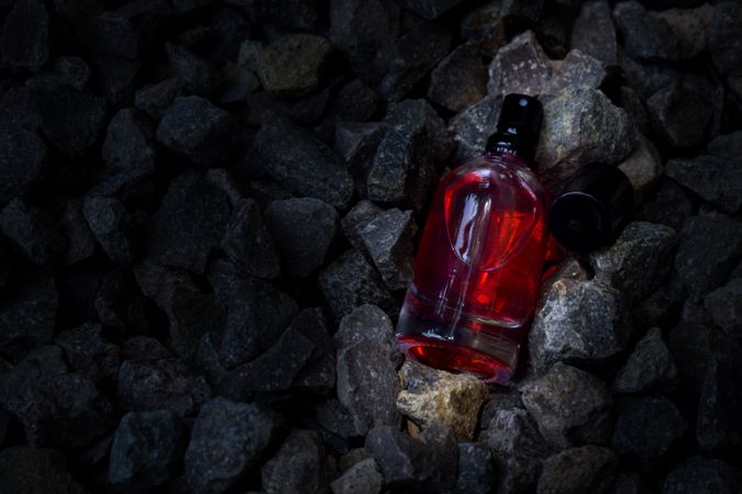 Red perfume bottle mock up laying in rocky terrain