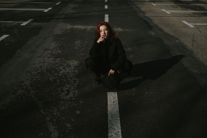 Smiling woman sitting on road with markings