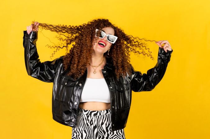 Smiling woman with curly hair in leather jacket wearing sunglasses