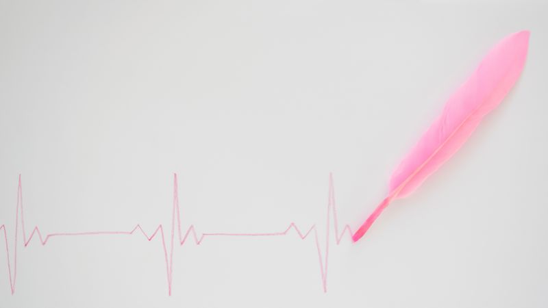 EKG with pink feather on blank background