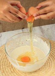 Person cracking egg into bowl of batter