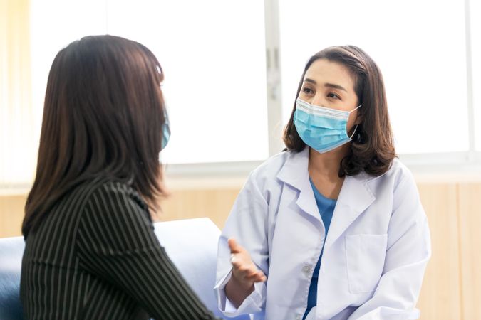 Doctor discussing treatment with patient, both are wearing face masks