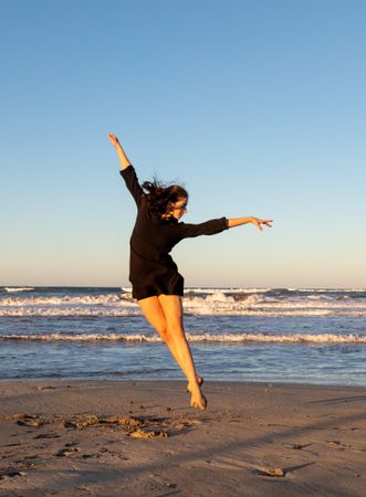 Young woman dancing and posing near water on shore