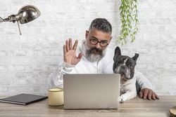 Man working on his desk from home with his dog bDMkK0