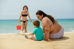 Mother and son playing with toys on sandy beach