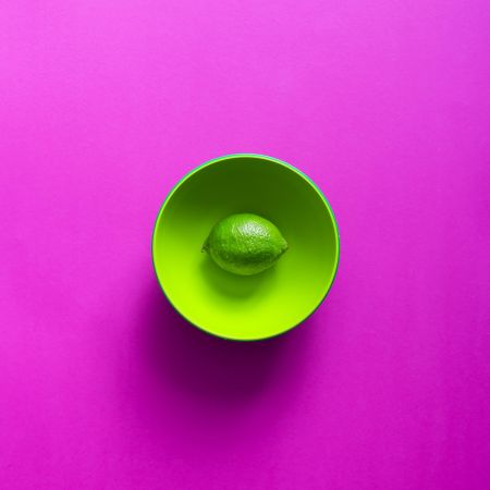 Lime in green bowl on purple background