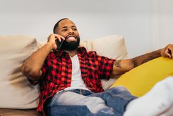 Black man making a call with smartphone relaxed at home
