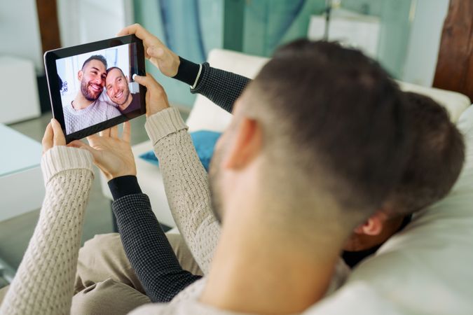 Male couple taking a selfie while relaxing on sofa