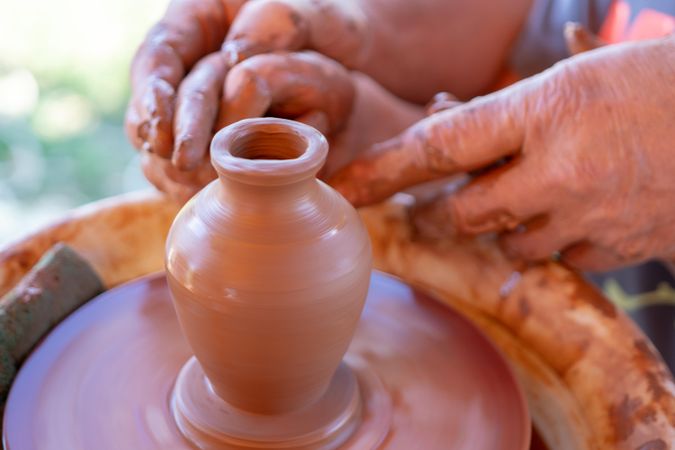 Person helping child's hands in making pottery