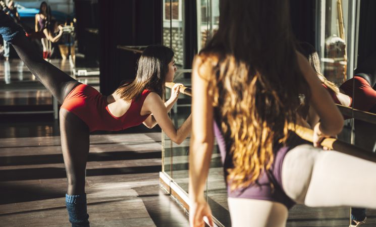Young fit women training and dancing ballet with barre.