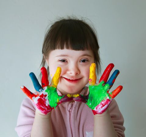 Portrait of a cute little girl using paints to draw on her hands