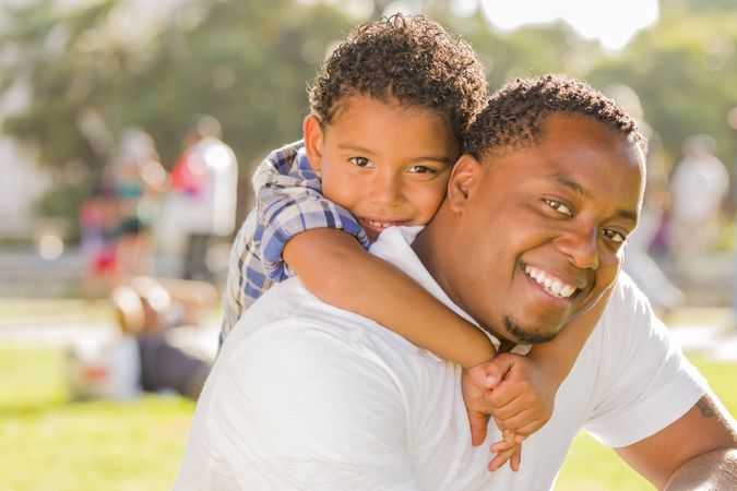 Black Father and Son Playing Piggyback in Park