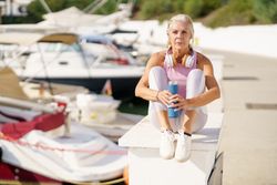 Mature female in sports clothing drinking water from a metal water bottle