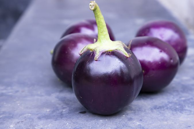 Fresh round eggplant on a grey concrete floor with selective focus