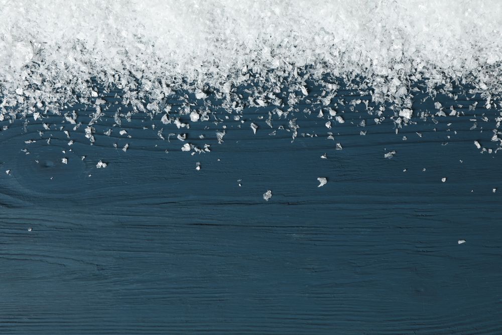 Snow on wooden background, space for text