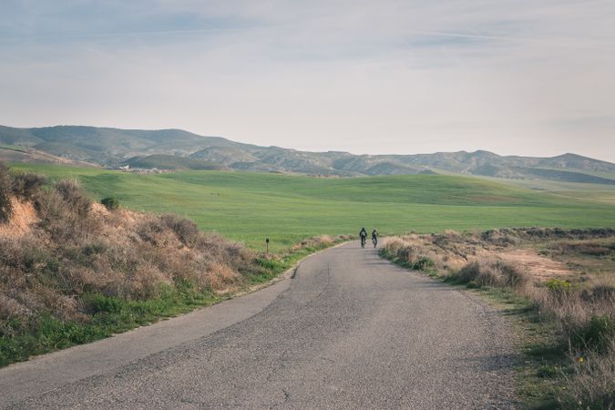 Men riding bicycles on road in desert hills