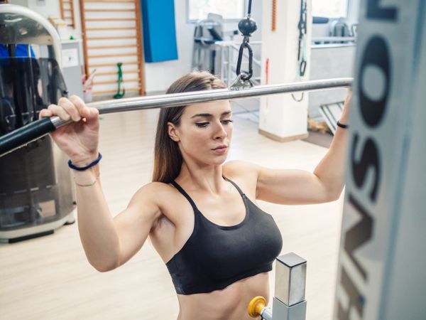 Fit woman doing lat pull-down exercise