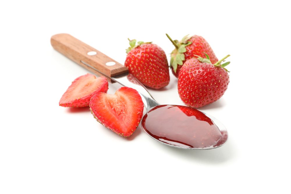 Strawberry and spoon with strawberry jam isolated on plain background