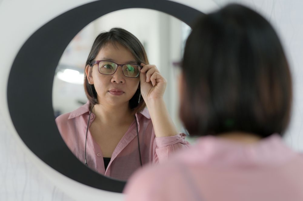 Young woman checking her eyesight and choosing glasses