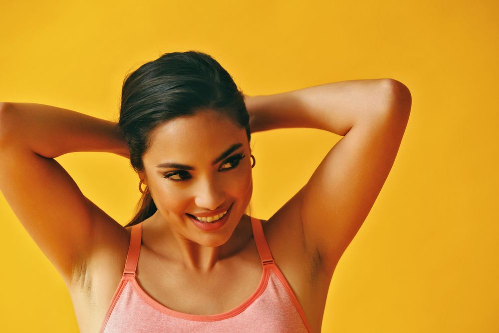 Headshot of Hispanic woman pulling her hair back into pony tail