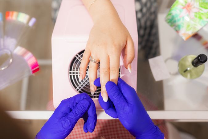 A female beautician's hands holding the hands of a client at the beauty salon