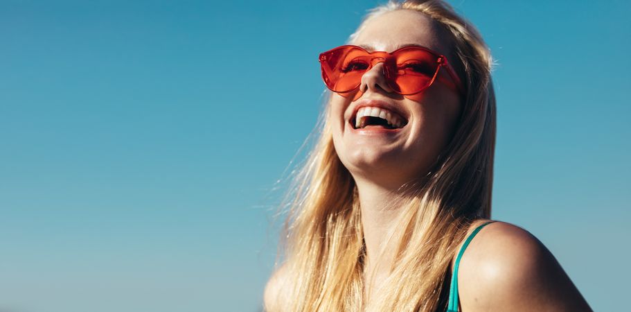 Close up of young woman in sunglasses looking away and laughing