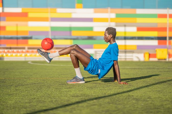 Black teenager bouncing football ball on foot