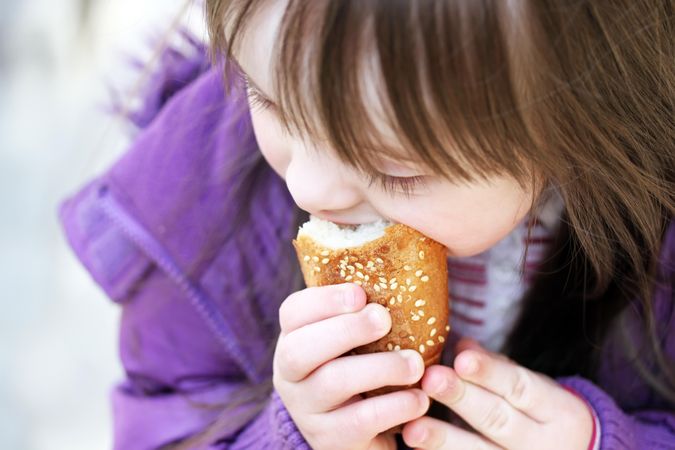 Portrait of a girl with Down syndrome biting into bread