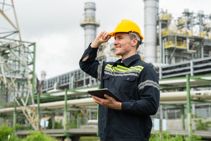 Refinery oil engineer worker in protection hardhat with digital tablet inspecting at petrochemical factory.