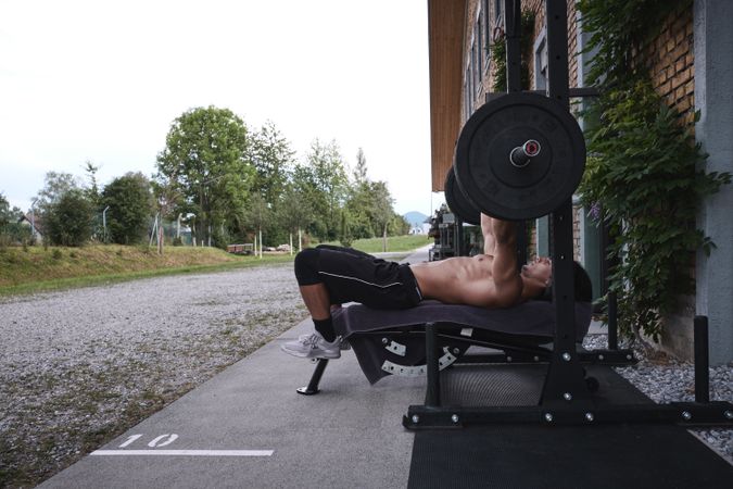 Man lifting barbell on street