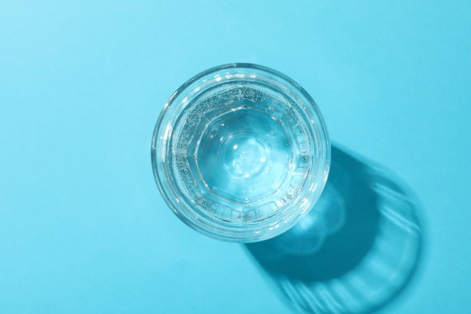 Looking down at full glass of water in blue room