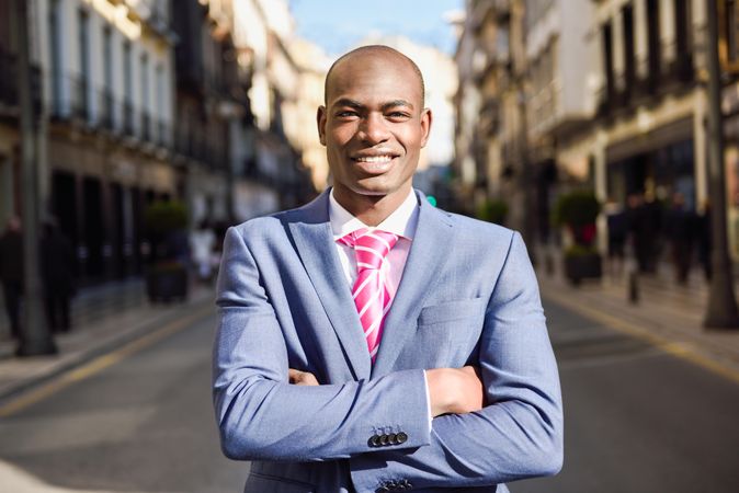 Happy male standing with his arms crossed on quiet street