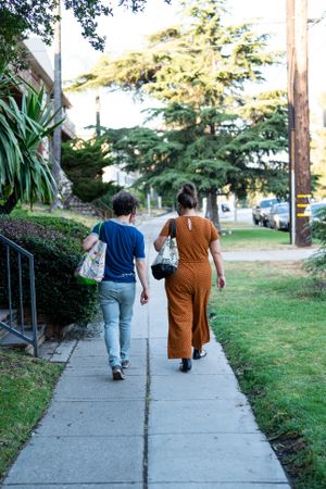 Back view full length of friends walking together after grocery shopping