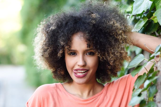 Portrait of funny Black woman with afro hairstyle in front of wall with vines