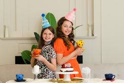 Two girls back-to-back in birthday hats