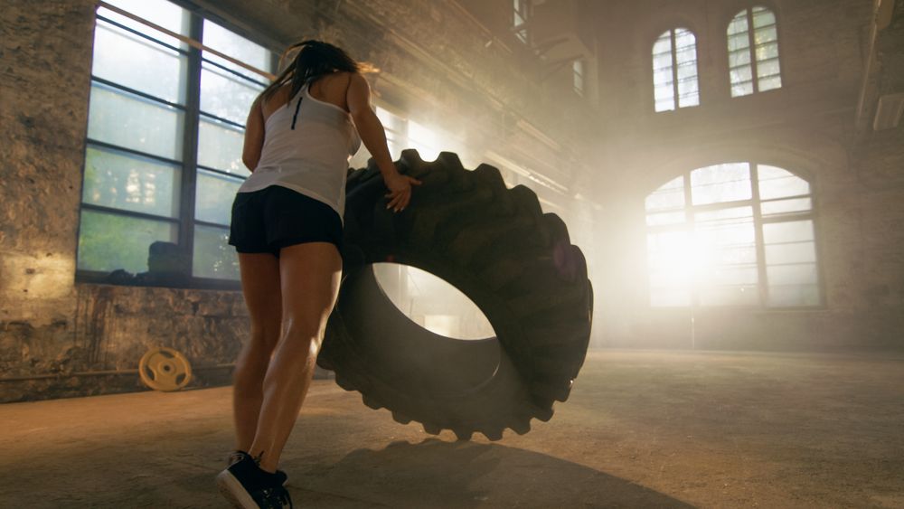 Fit Athletic Woman Lifts Tire as Part of Her Cross Fitness  Bodybuilding Training.