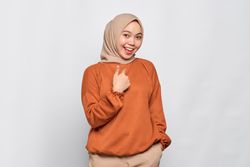 Happy woman in hijab and orange shirt in studio