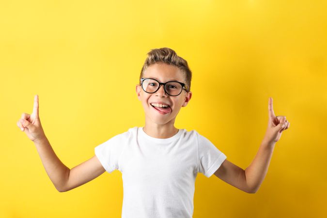 Happy boy in glasses against yellow background, space for text