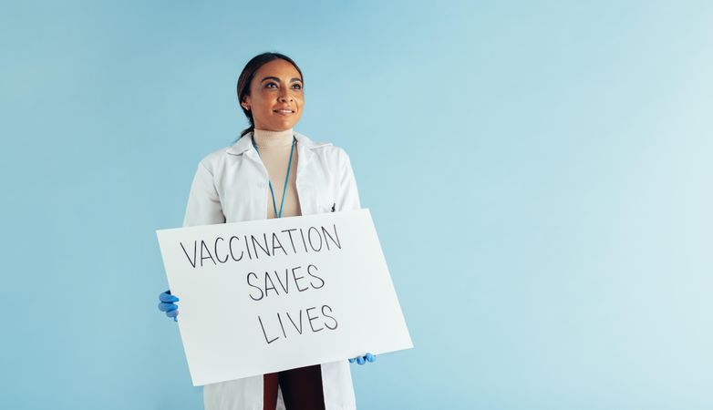 Vaccination saves lives poster board in hands of a woman doctor