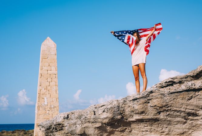 Peaceful patriotic female traveler enjoying in vacation at rocks