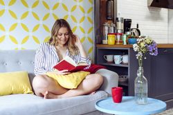 Young happy female reading book on sofa