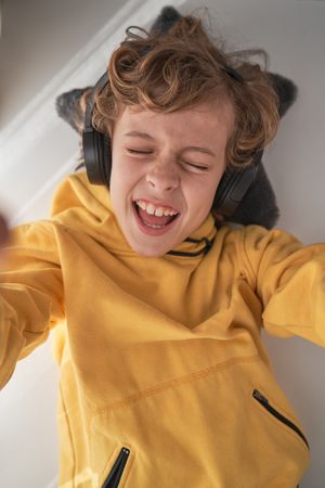 Content kid enjoying music in wireless headphones and taking sel