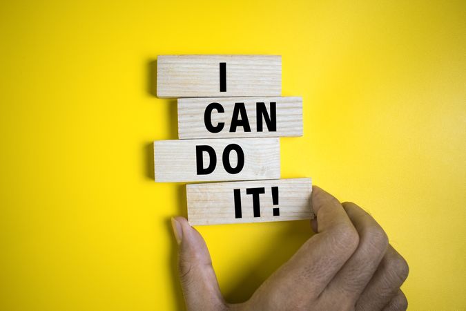 male hand put wooden blocks with i can do it words isolated on yellow background