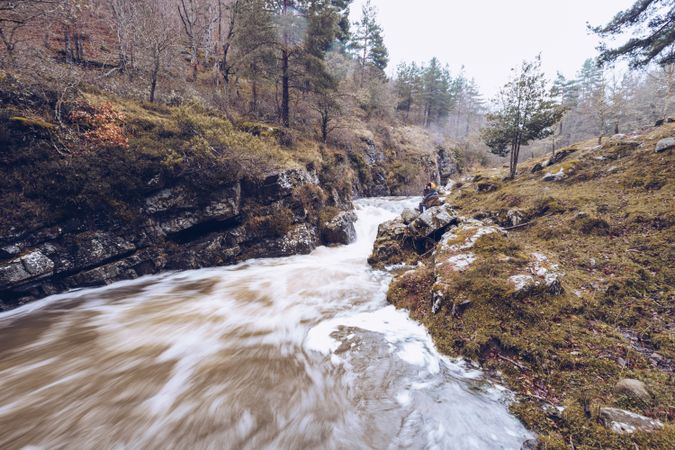 Woman gazing at fast mountain river in forest