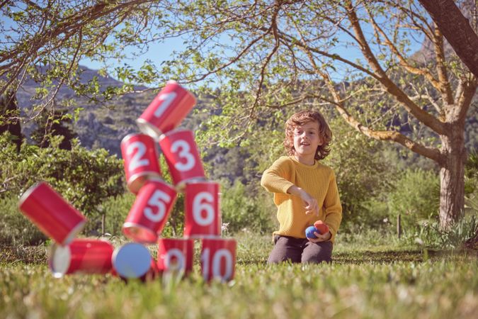 Content boy playing can knockdown game in summer park